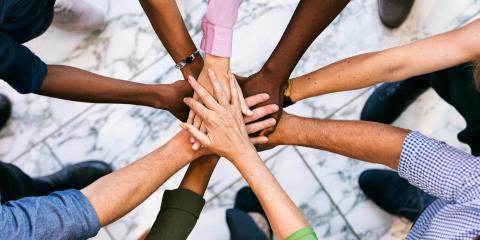 Group of people lined up in a circle and put their hands on top of each other.