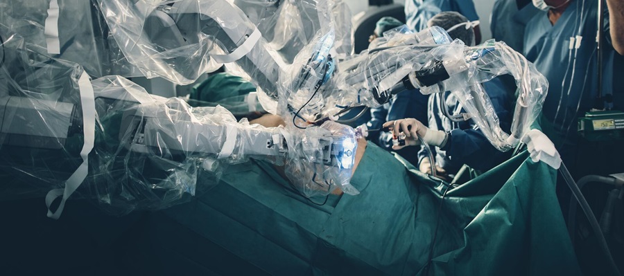 Foto eines OP-Tisches mit hirurgischen Robotern, die eine Operation durchführen und mit speziellen Foilien isoliert sind.