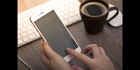 Nahaufnahme von zwei Händen, die ein Smartphone bedienen.