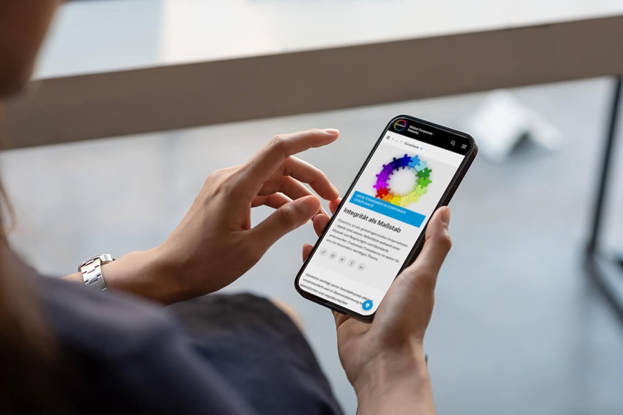 Person hält Smartphone mit farbigem Kreisdiagramm und 'Guided by Integrity' Text auf dem Bildschirm